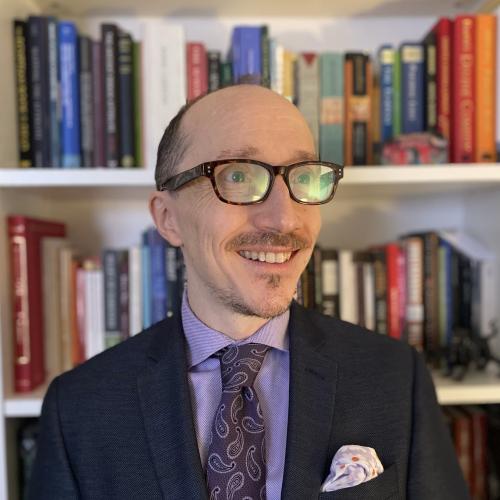Photo of Dr. Benjamin Eldon Stevens in front of bookcase